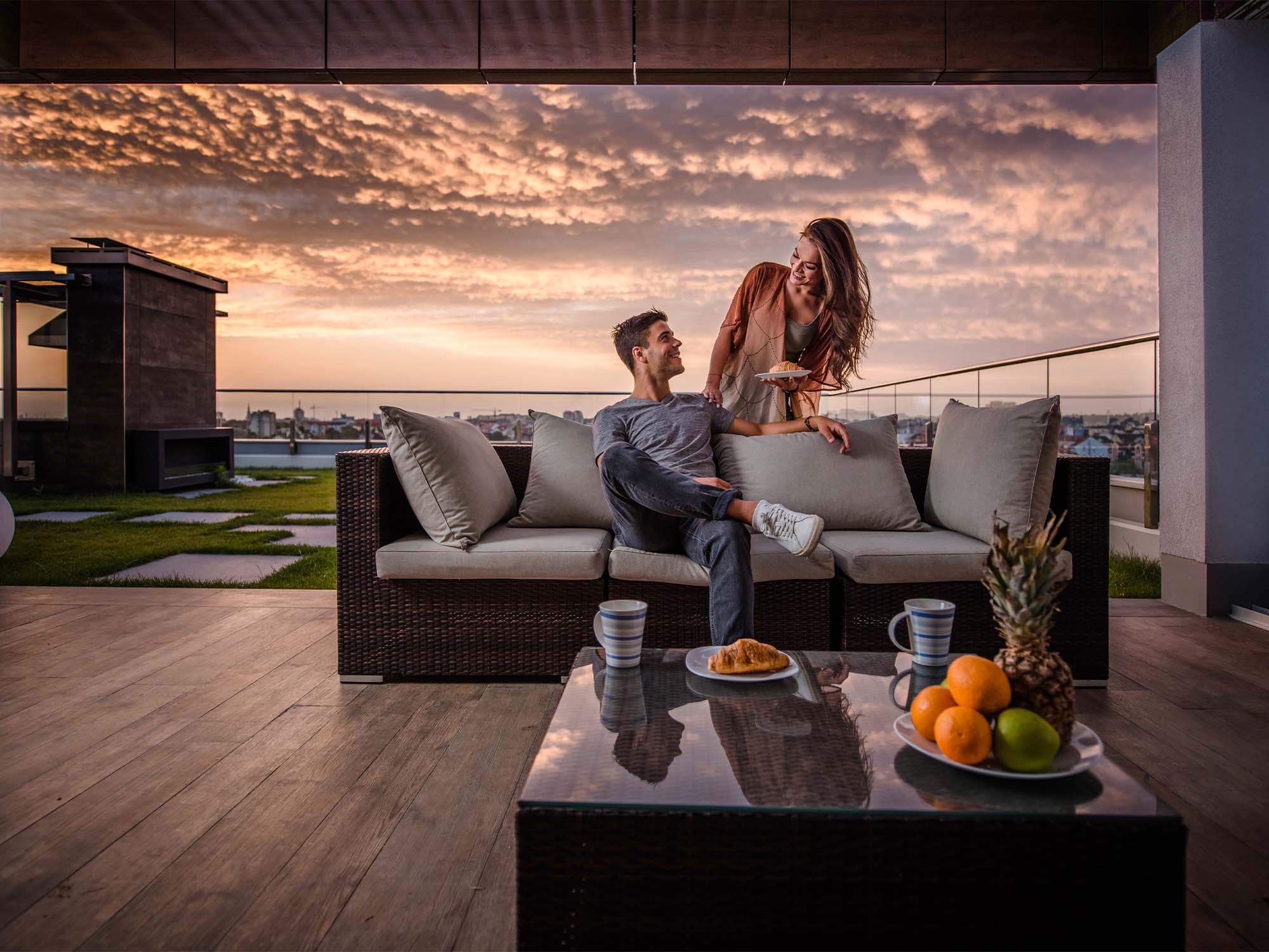 image of a couple enjoying food and sunset on an open deck of a high rise building 